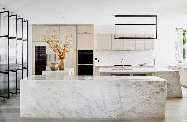 Ultra-modern kitchen with a large marble island, minimalist cabinets, and unique lighting.
