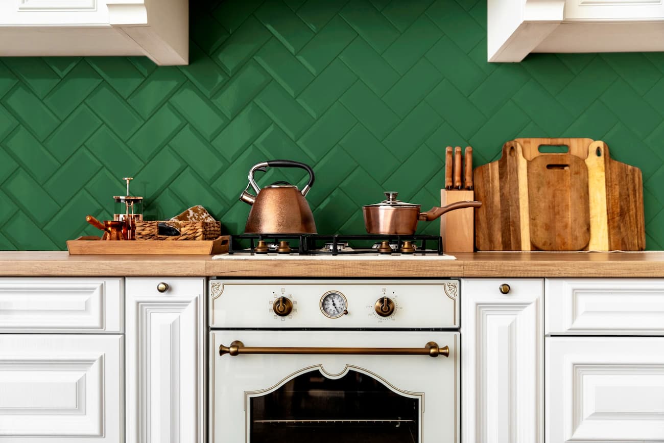 Kitchen counter with white cabinets, wood countertop, and green subway tile backsplash.